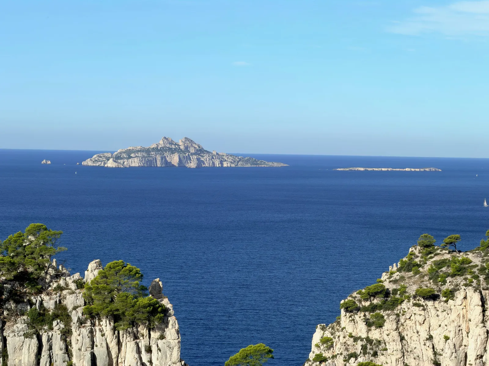 Île rocheuse à l’horizon, au-delà de la mer bleue.