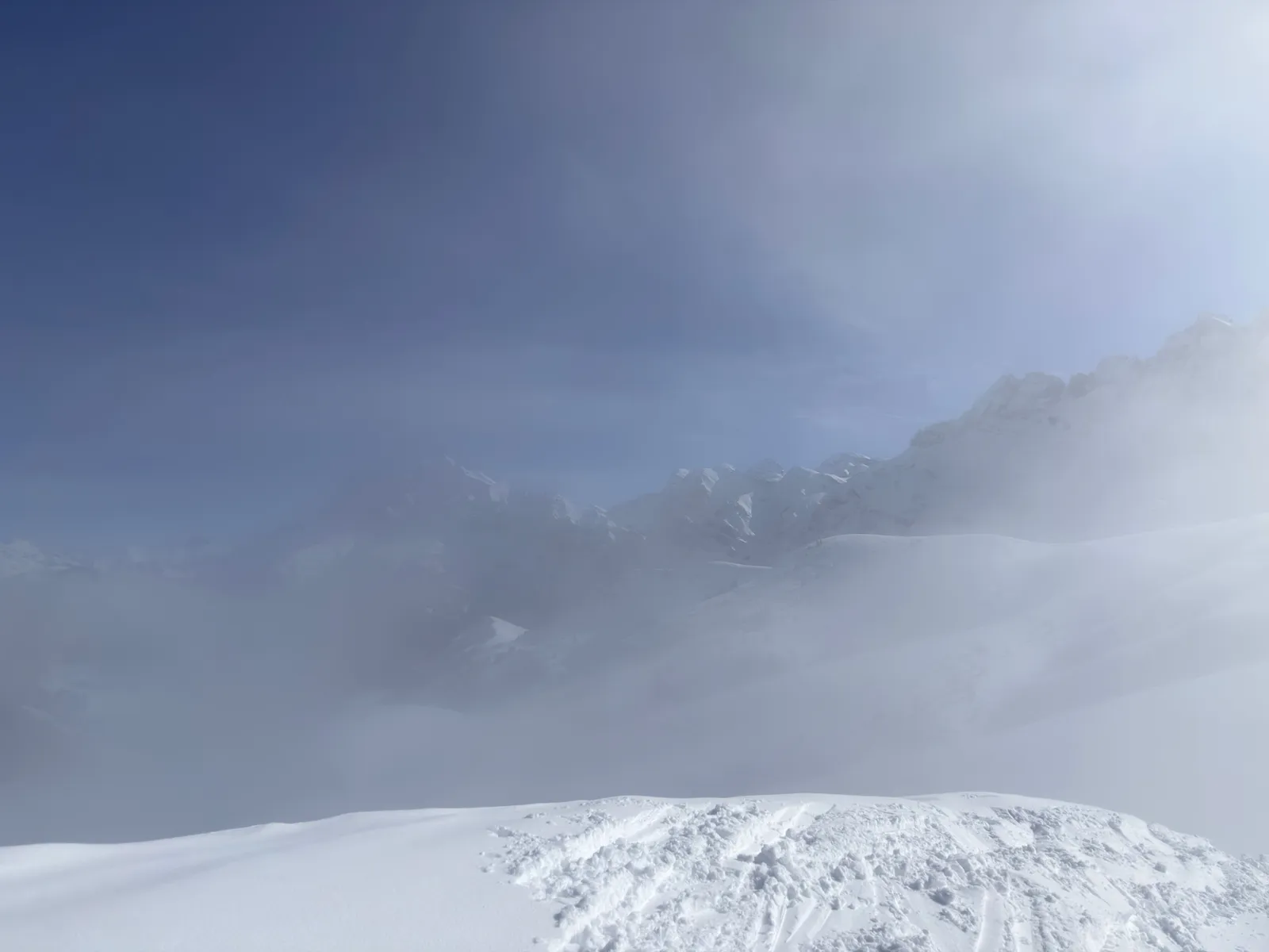 Reliefs enneigés apparaissant dans la brume depuis le col de Coux