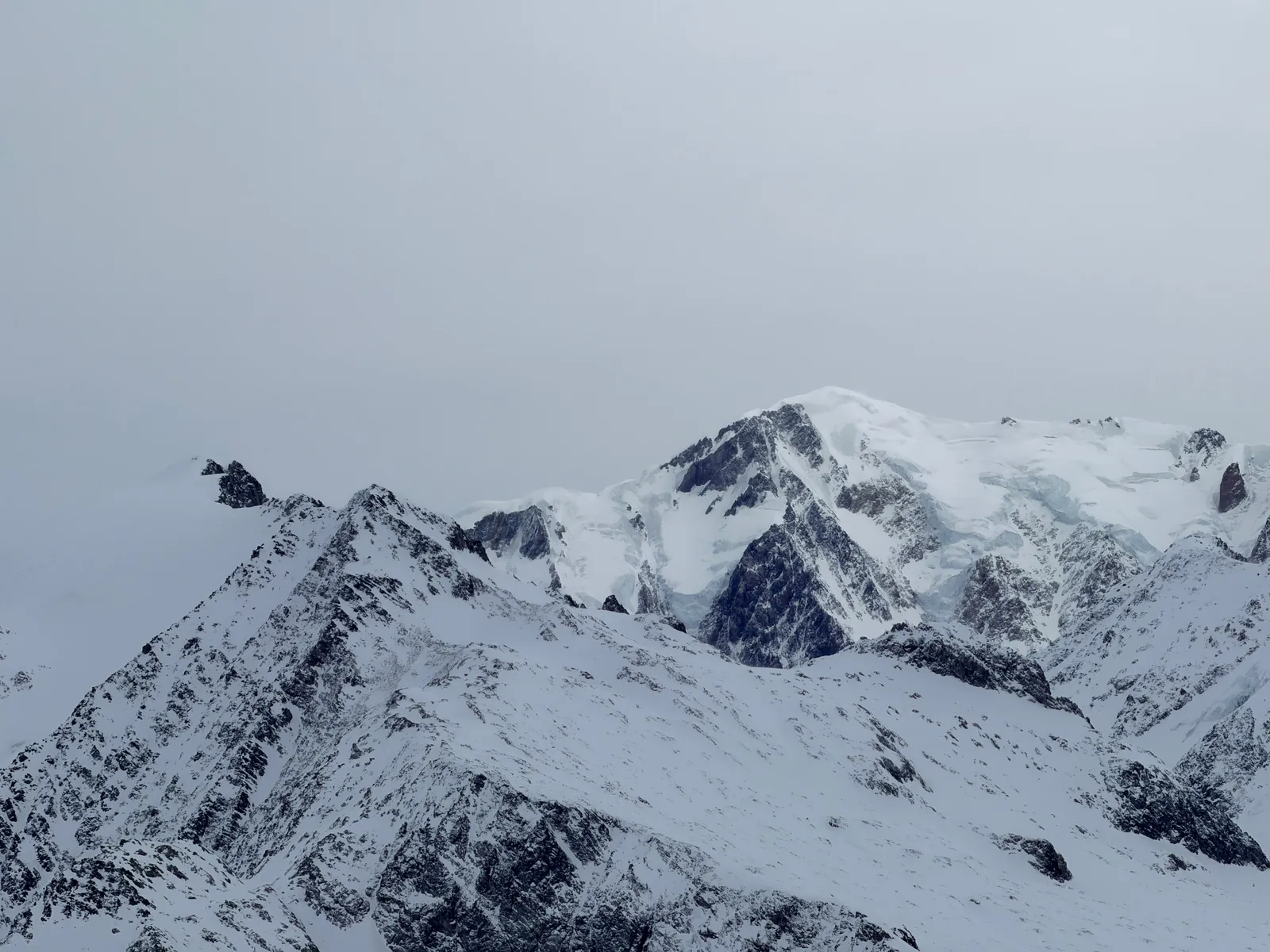 Sommets et glaciers enneigés sous un ciel couvert depuis le parcours du col de la Fenêtre.