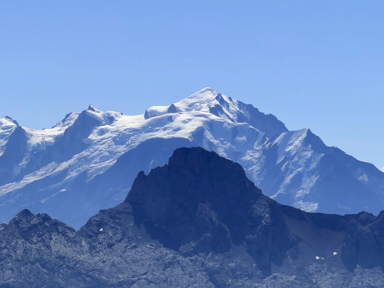 Mont-Blanc enneigé au-dessus de crêtes rocheuses plus sombres.
