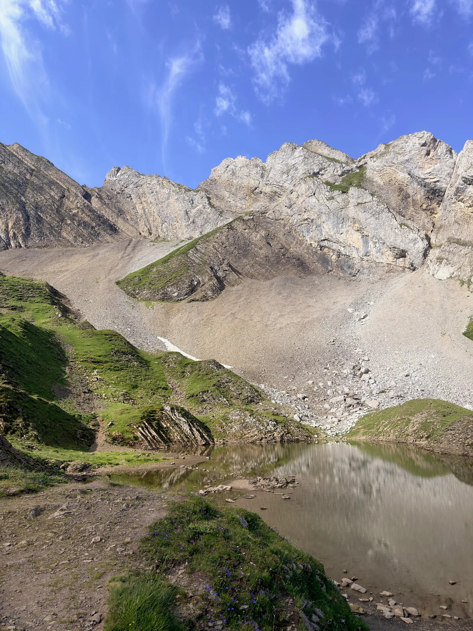 Lac de Tardevant au pied d’une falaise calcaire, avec les rochers reflétés dans l’eau.