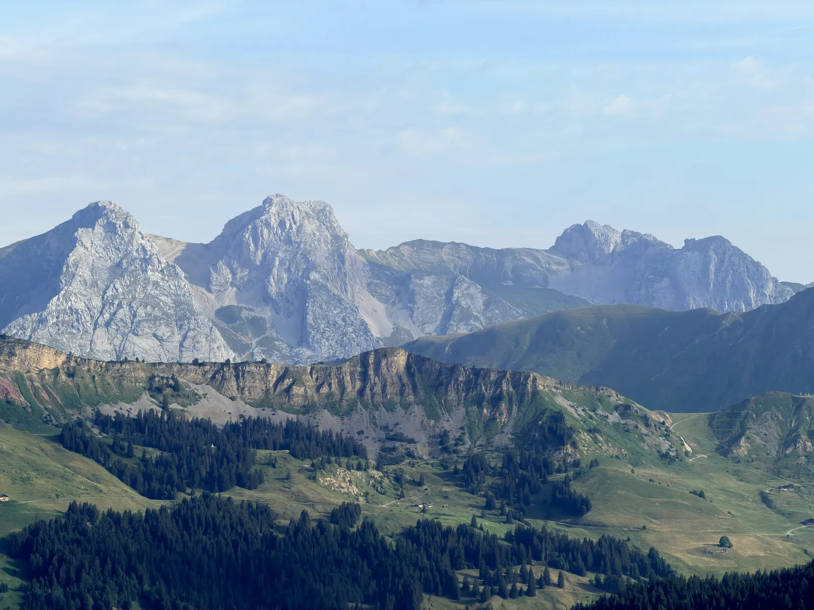 Reliefs calcaires en arrière-plan des alpages et des forêts.
