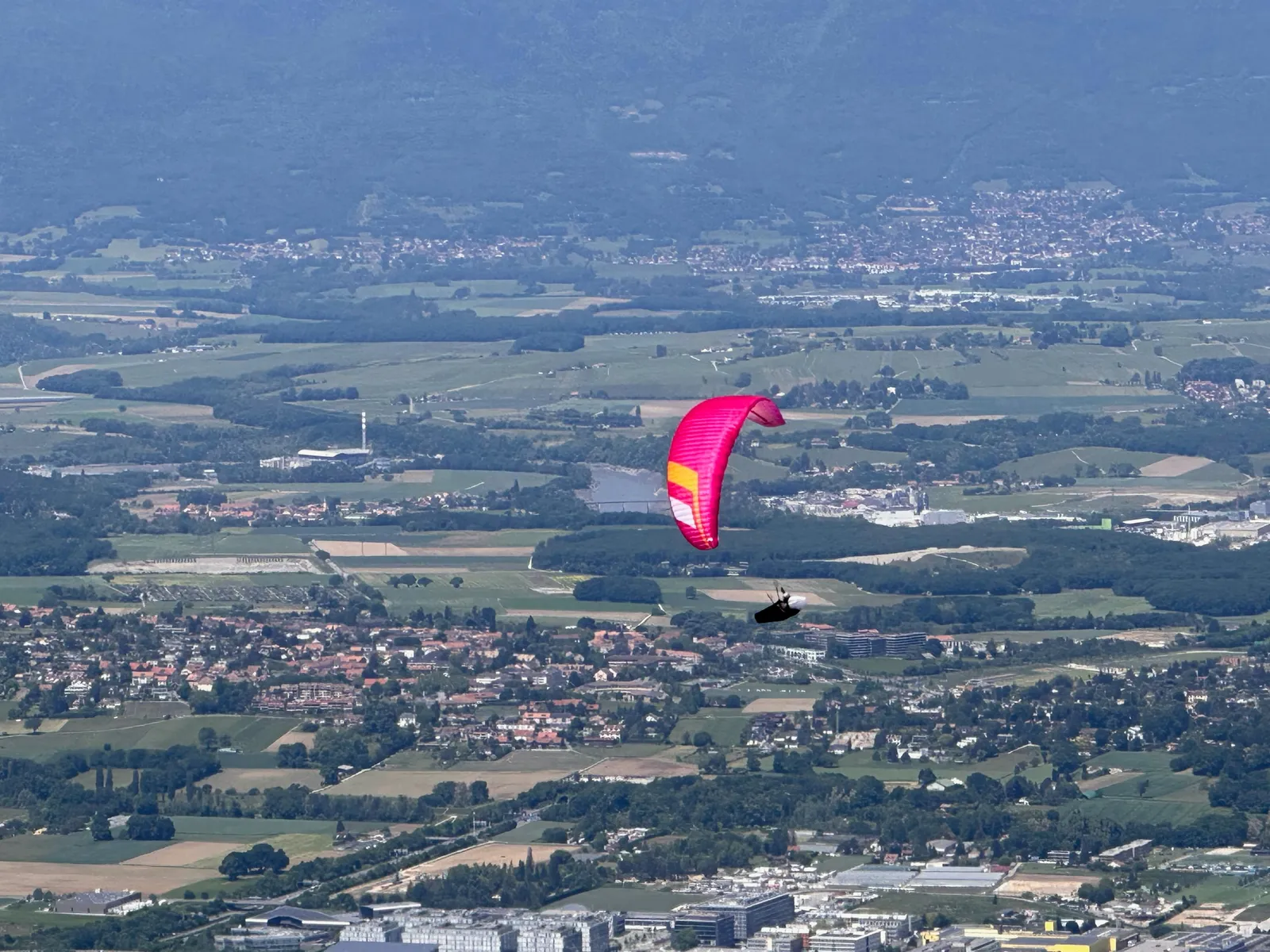 Parapente au-dessus des champs et des villages au pied du Salève.
