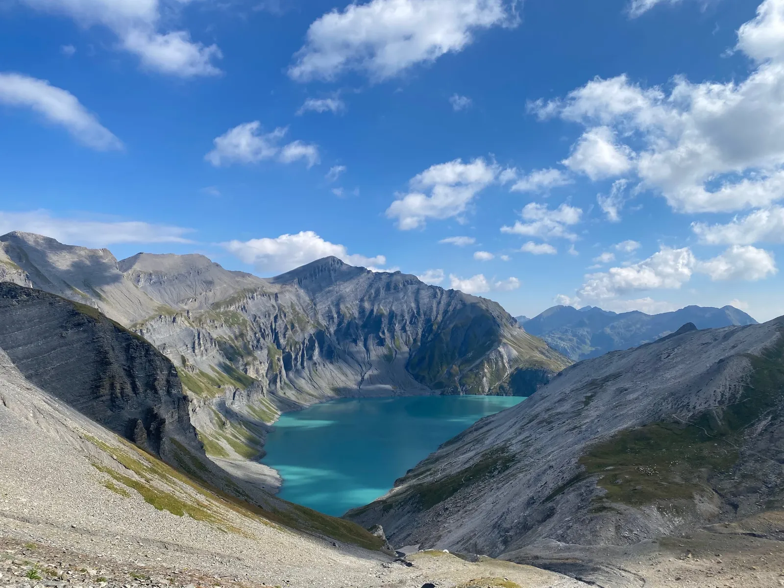 Lac turquoise encaissé entre des versants rocheux, vu depuis les hauteurs.