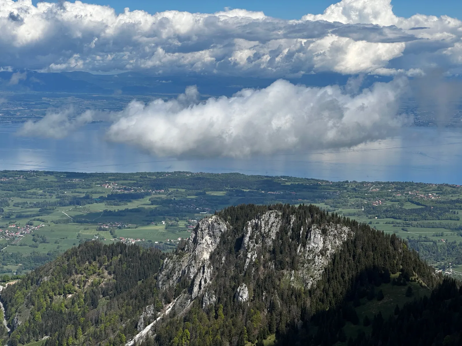 Sommet rocheux et pentes boisées sous les nuages.
