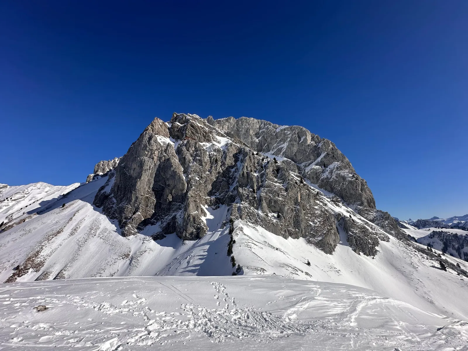 Sommet rocheux et traces de ski dans les pentes de neige.
