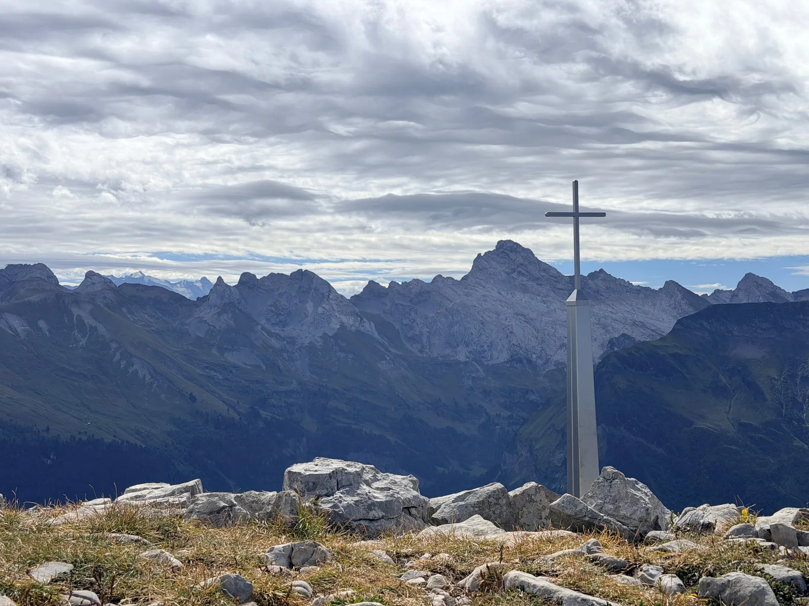Croix sur les rochers, face aux reliefs des Bornes et des Alpes.