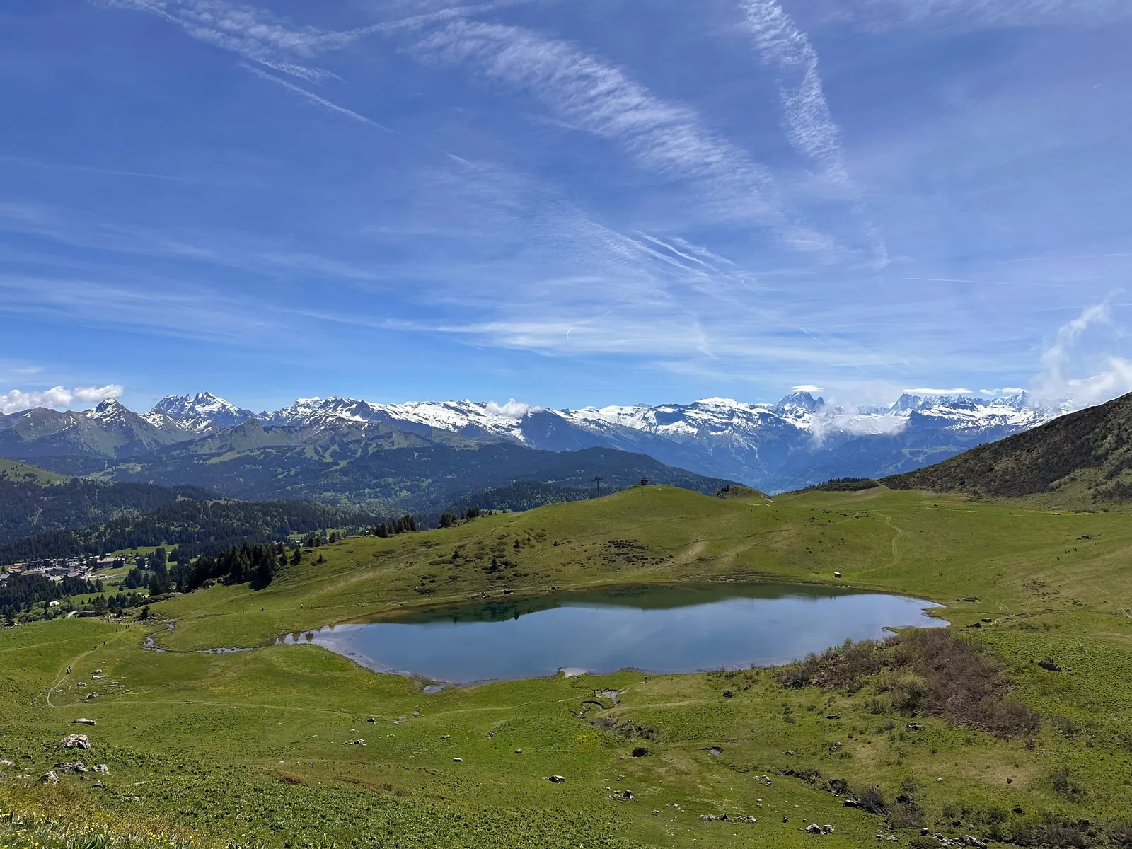 Lac de Roy au milieu des alpages, face aux montagnes enneigées.