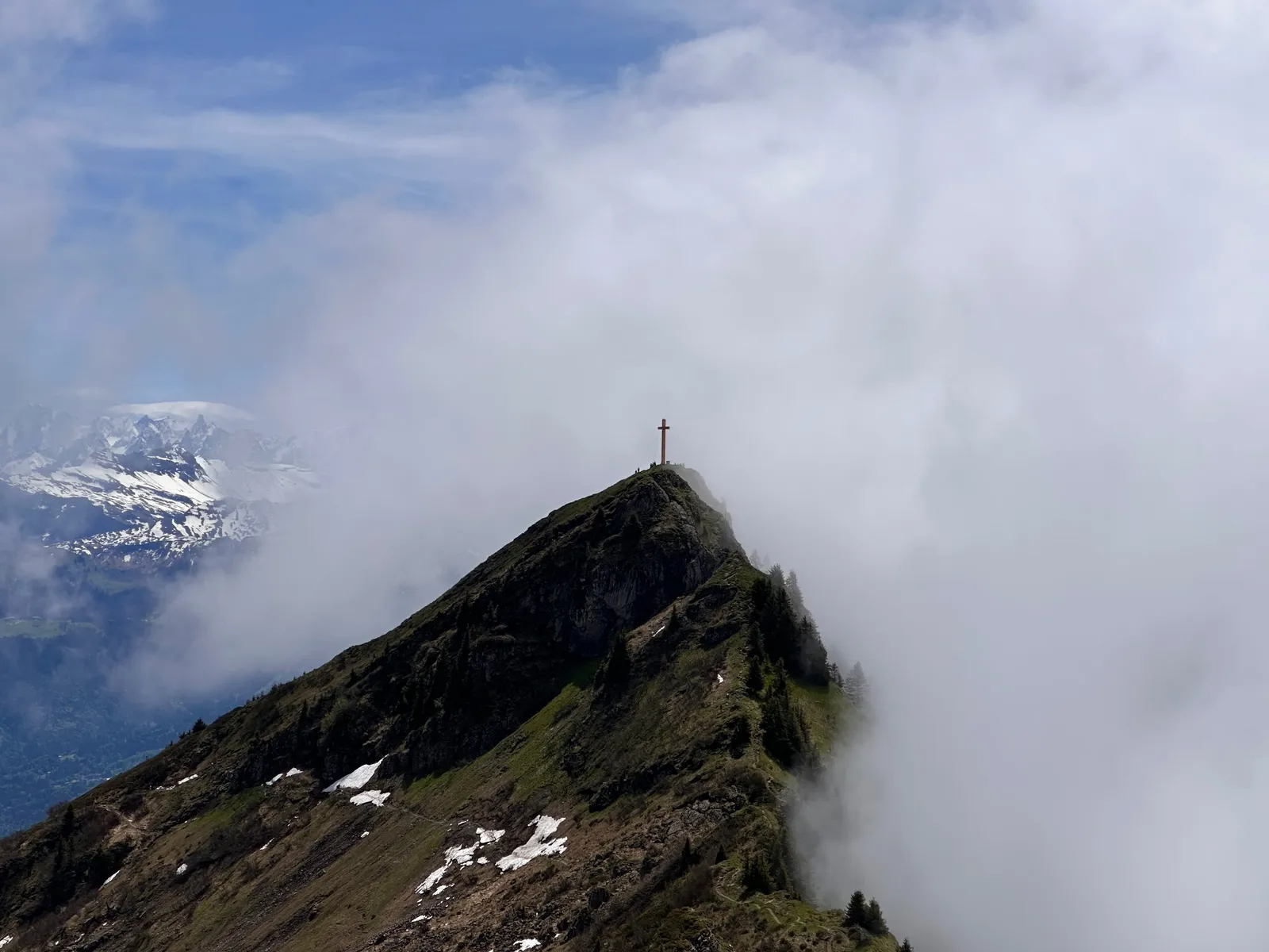 Croix du Pic Marcelly sur le sommet rocheux, à la lisière des nuages.