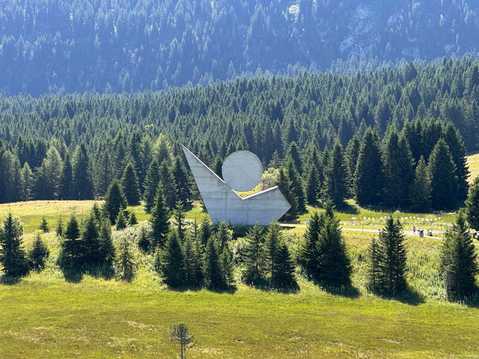 Monument au milieu des prairies et des conifères du plateau des Glières.