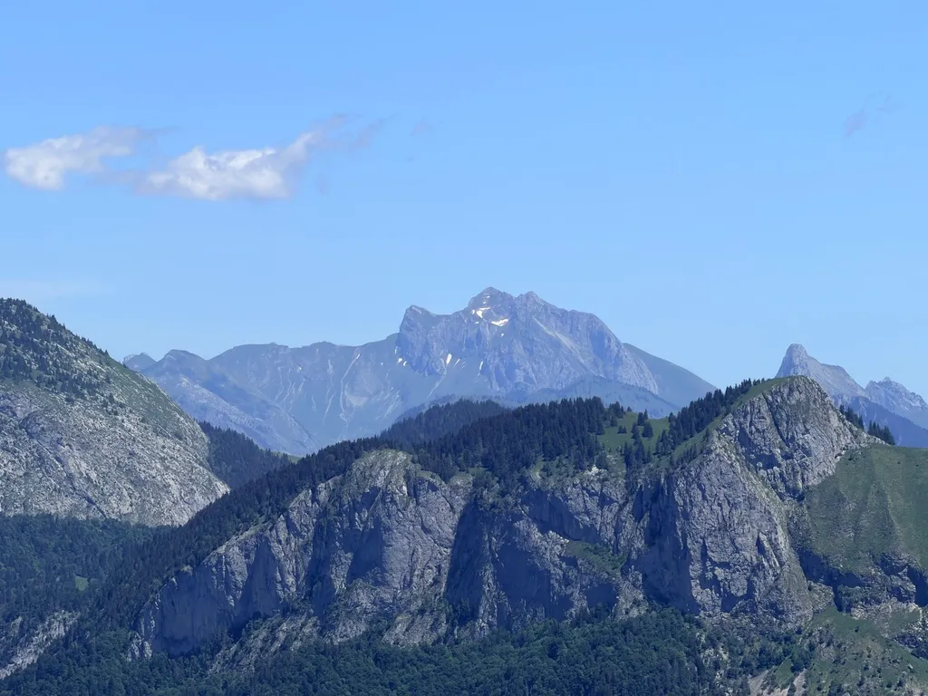 Succession de reliefs rocheux et de crêtes boisées sous un ciel bleu.