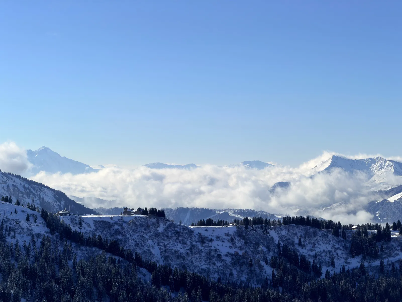 Nuages dans les vallées au-delà des chalets et des forêts enneigées