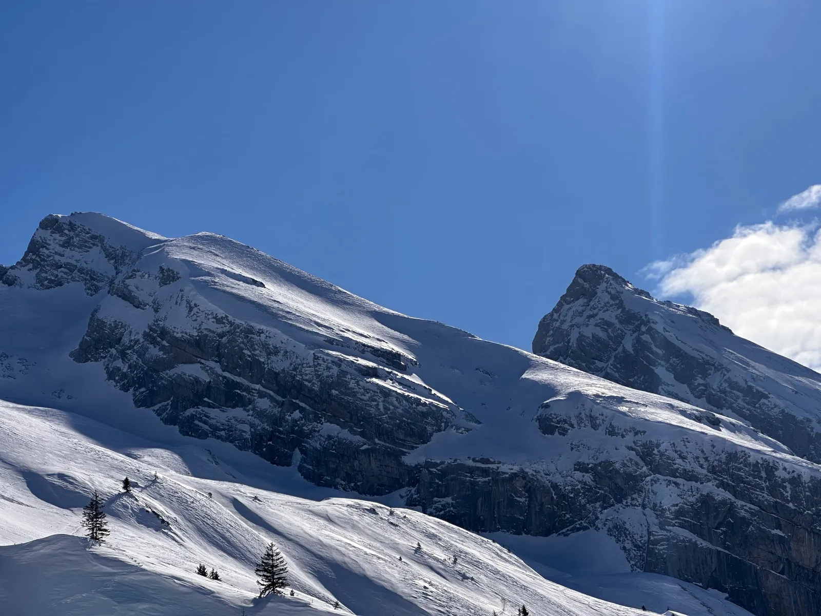 Parois rocheuses et pentes enneigées sous un ciel bleu.
