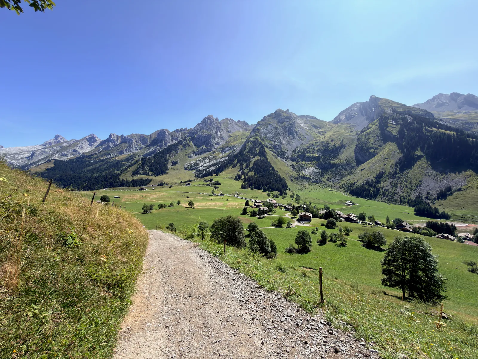 Chemin de gravier descendant vers les chalets et les alpages des Confins, face aux reliefs des Aravis.